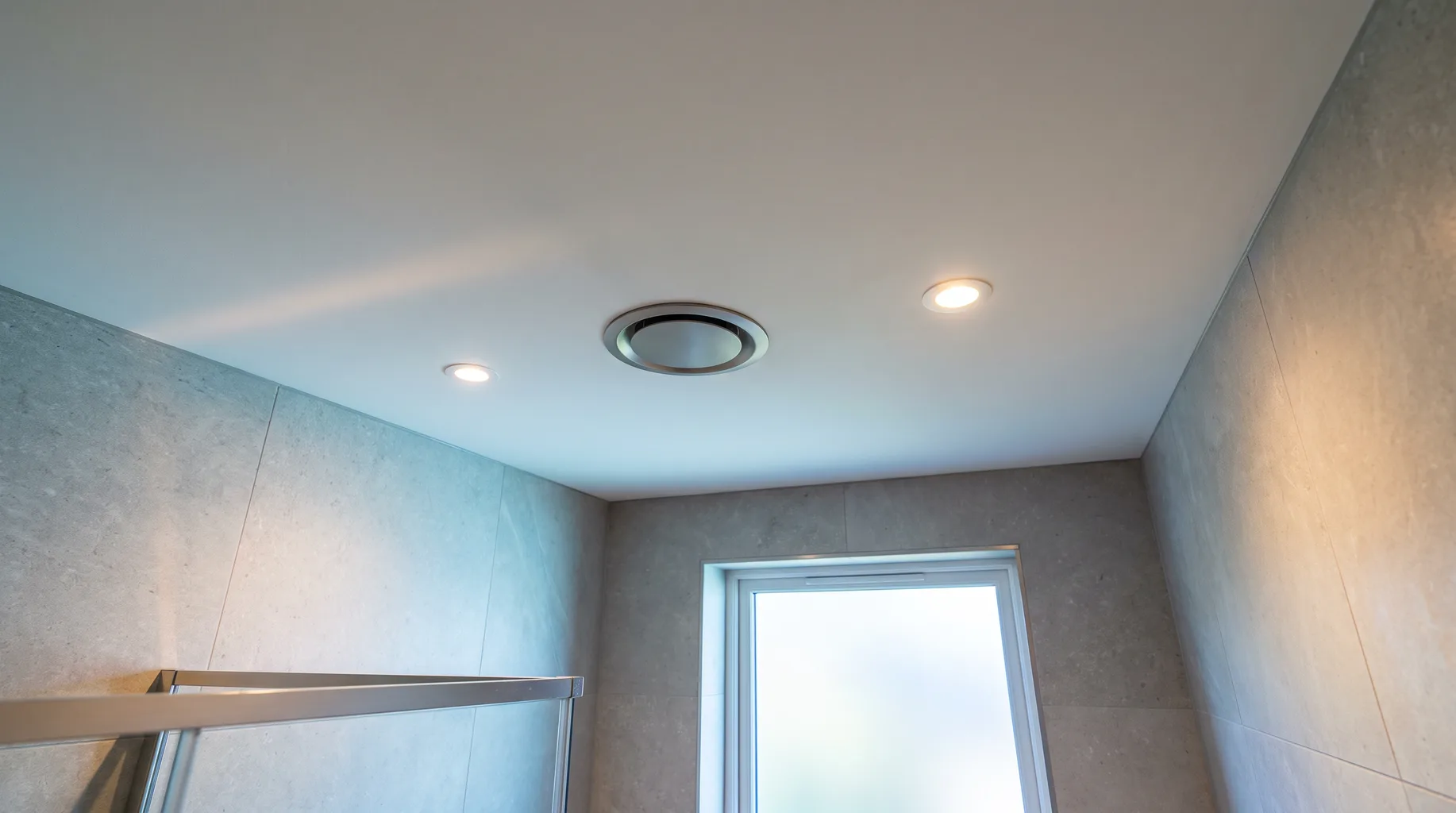 Flush-fitted bathroom ceiling extractor fan grille between recessed downlights in a finished luxury bathroom