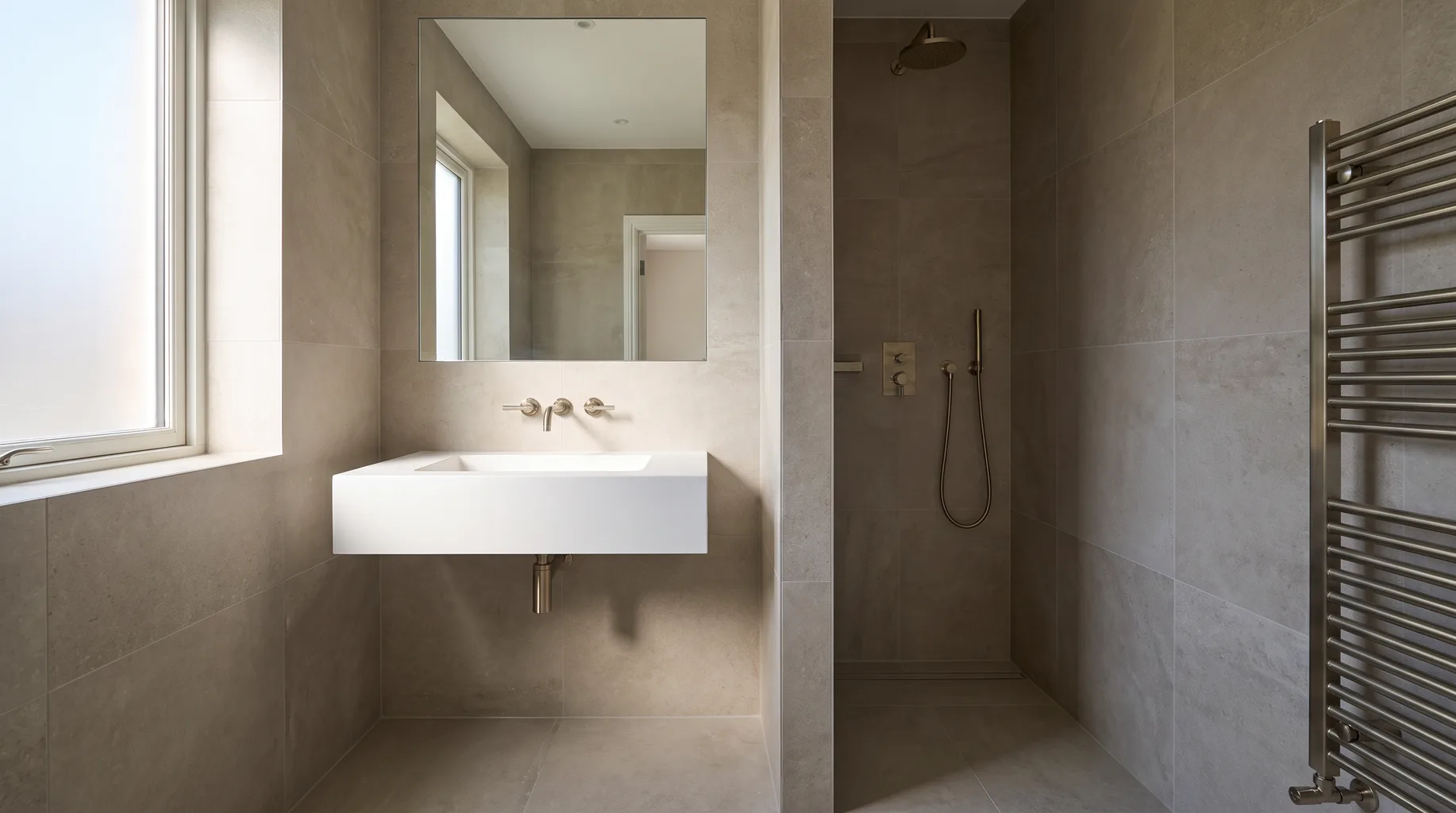 Finished luxury en-suite bathroom with wall-hung basin and walk-in shower, built to the same standard whichever route supplied the products