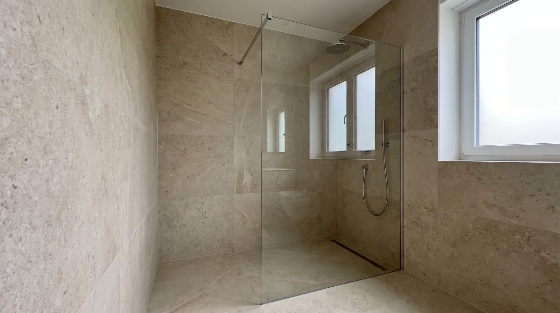 Finished walk-in shower enclosure with a frameless glass screen against tiled walls