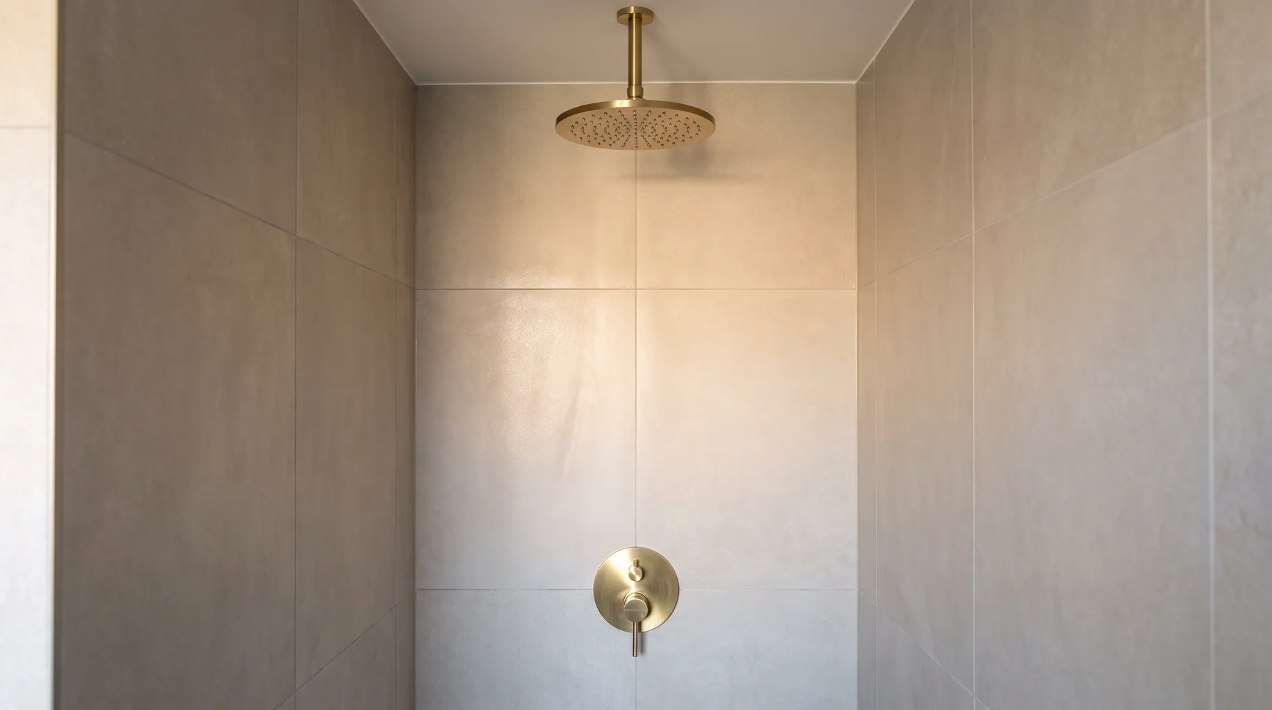 Finished walk-in shower enclosure with wall-mounted valve and overhead rainfall head
