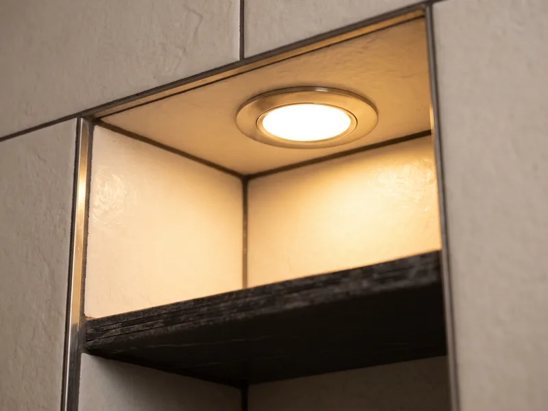 Close-up of recessed niche lighting in a tiled shower wall