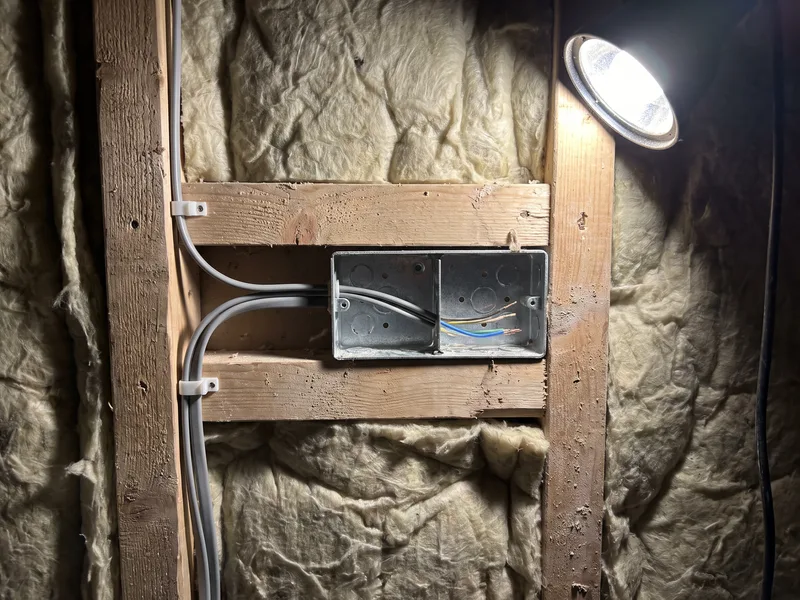 Close detail of an electrical back box and cable set into a stud wall cavity during bathroom first-fix