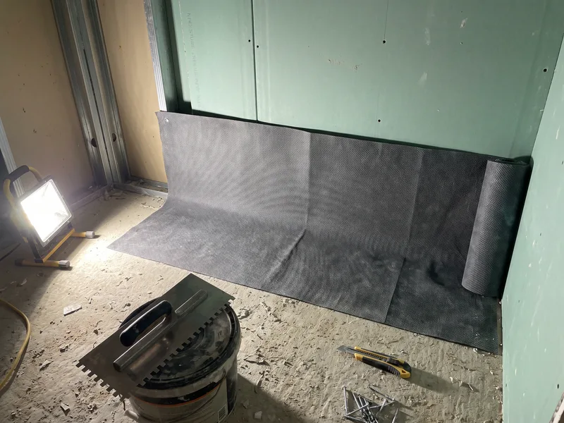 Close detail of a waterproofing tanking membrane being applied to a stud wall during a bathroom first-fix stage