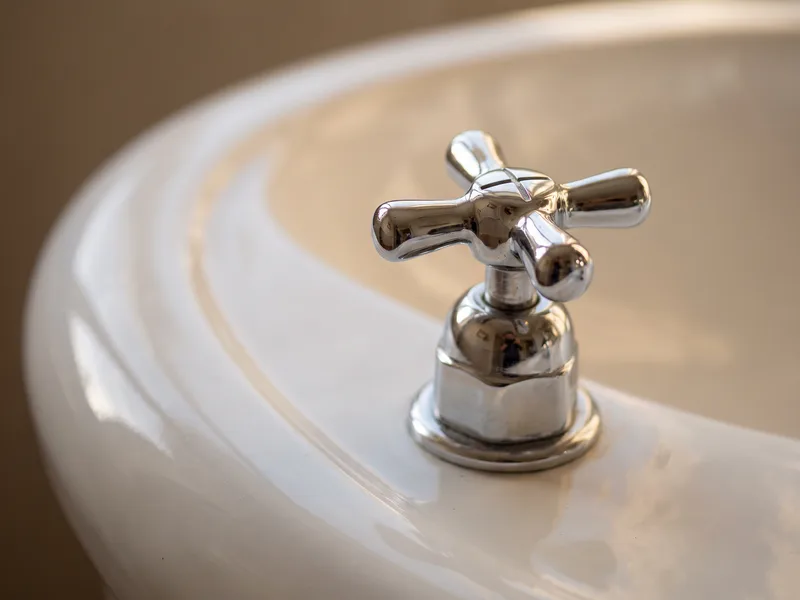 Macro close-up of a traditional cross-head tap handle on a Burlington pedestal basin