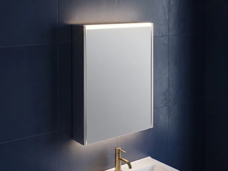 Close detail of an illuminated mirror cabinet mounted on a navy tiled wall above a basin