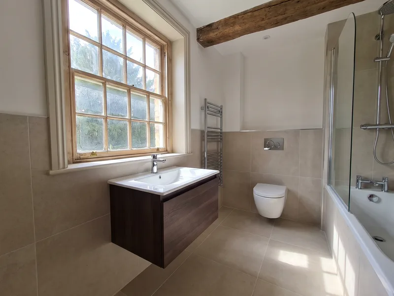 Finished compact luxury bathroom with a floating vanity unit beneath a sash window in a period Eton property