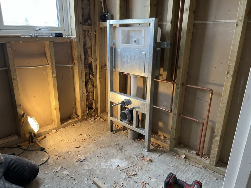 Free-standing concealed cistern carrier frame fixed to the floor and plumbed at first fix, before boarding and tiling