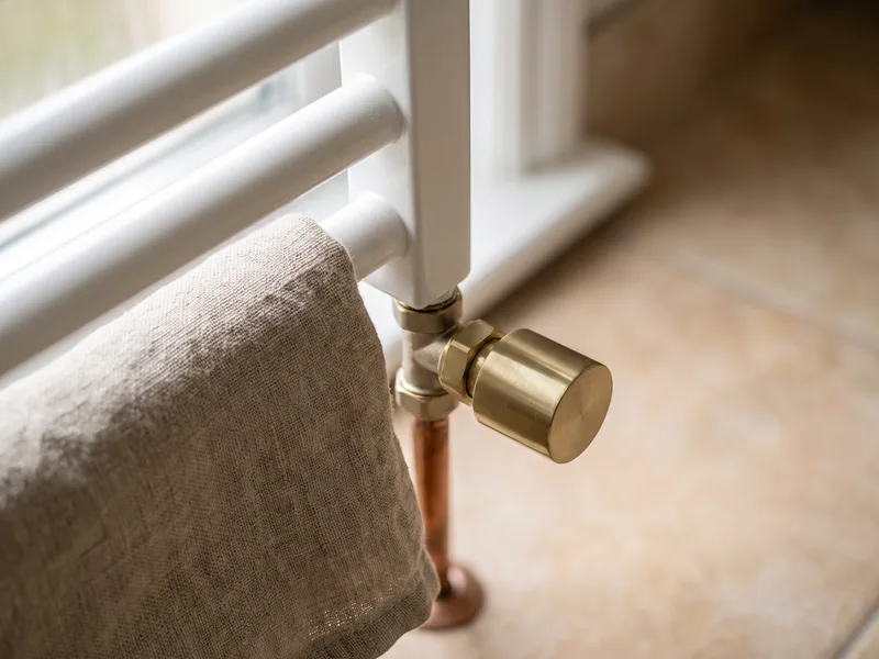 Close-up of a heated towel radiator's angled valve