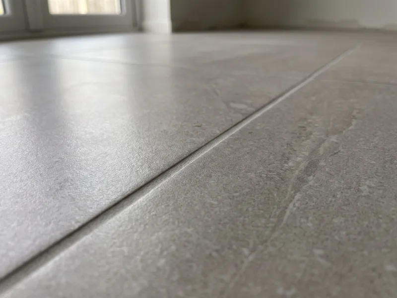 Macro view of a large-format porcelain tile surface and a tight grout joint to the adjacent tile