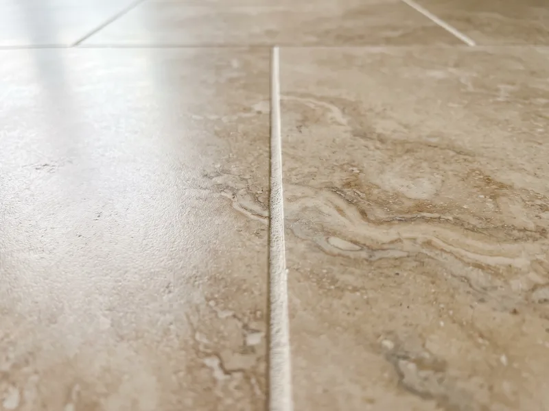 Macro view of a honed natural stone tile surface showing veining and a tight grout joint