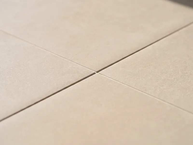 Macro close-up of two adjoining large-format Porcelanosa porcelain tiles meeting at a thin flush grout joint
