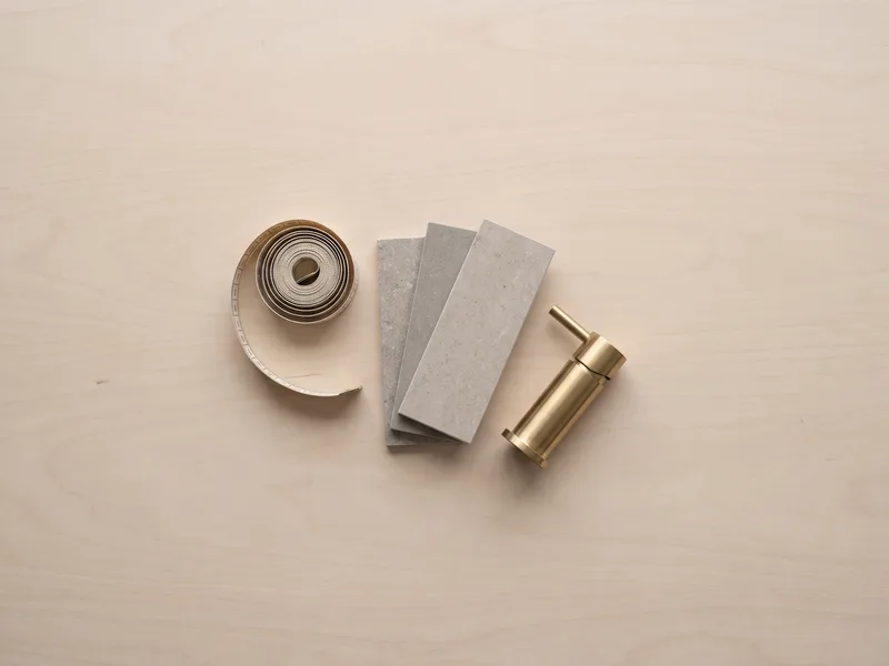 Overhead flatlay of a tape measure, tile samples and a brass tap sample used in a pricing consultation