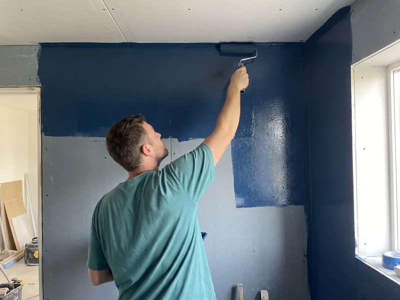 Installer applying liquid tanking membrane floor to ceiling on a steam shower enclosure under construction