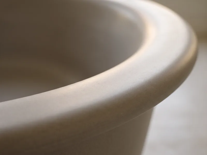 Macro close-up of the rolled rim edge of a freestanding Victoria + Albert stone-resin bath