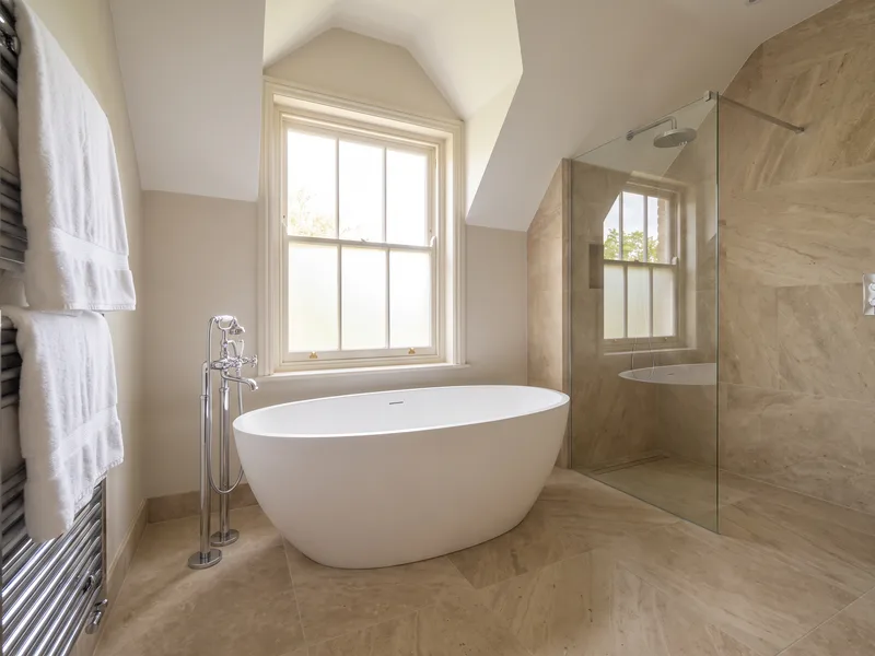 Finished luxury en-suite with a freestanding bath beneath a sash window in a Warfield period property