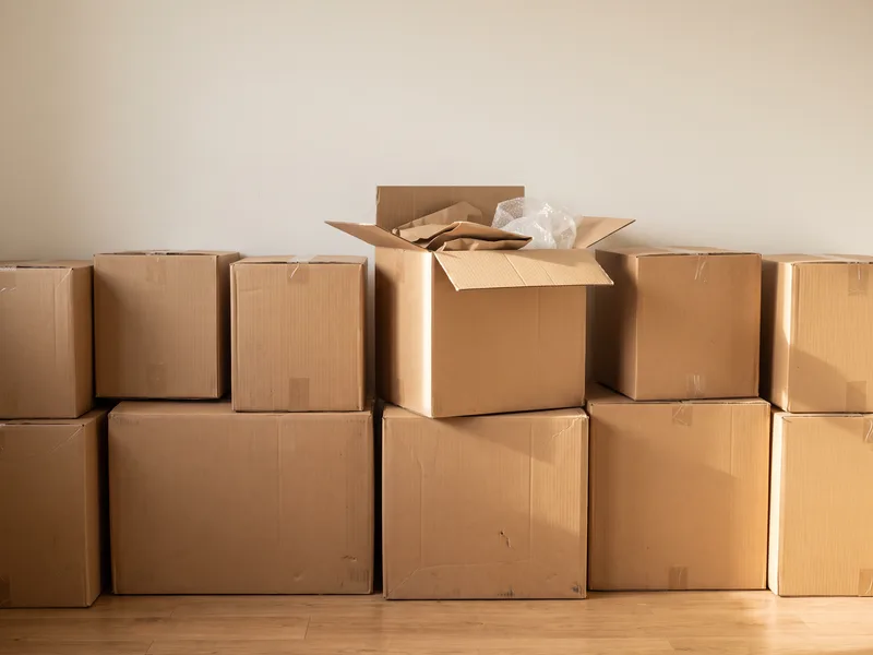 Cardboard boxes staged and stacked safely in a spare room ahead of a bathroom installation