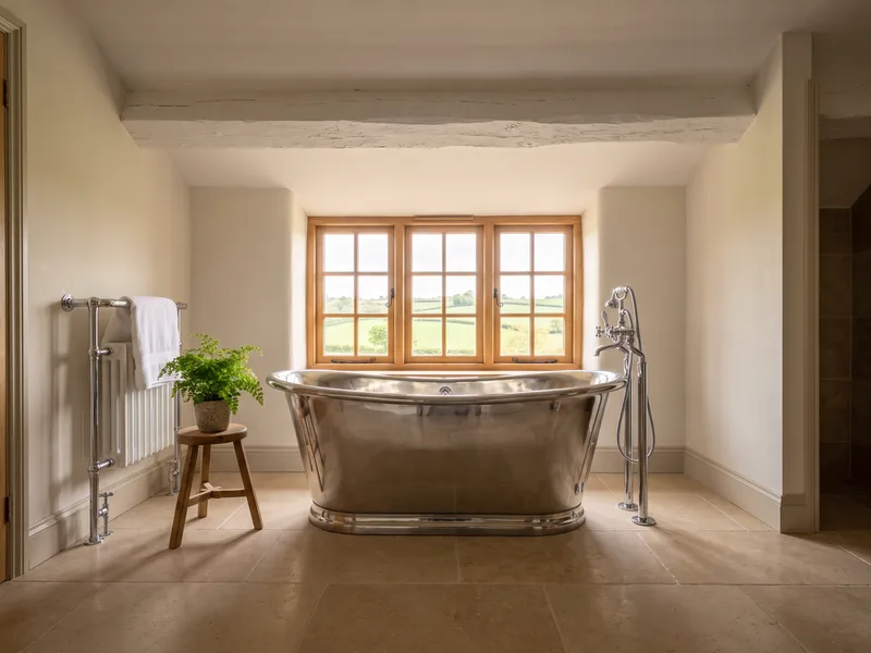 Finished rural en-suite bathroom with a countryside-facing window and freestanding bath in a Winkfield period property